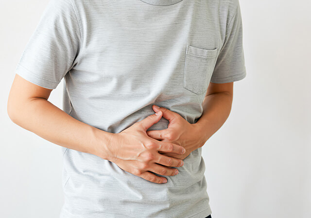 痛みを感じて腹を押さえている男性